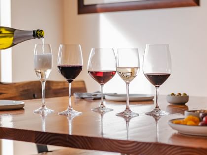The Vino Grande series on a table top filled with wine with a hand pouring champagne into the champagne glass.