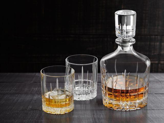 The with Whisky filled SPIEGELAU Perfect Serve Collection decanter next to two Perfect tumblers, one filled with Whisky on the rocks.<br/>