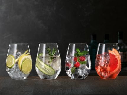 SPIEGELAU Gin and Tonic glasses on a wooden sideboard, each of thm filled with a different Gin Cocktail.<br/>