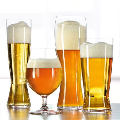 The four SPIEGELAU Beer Classics glasses in a row, pilsner, beer tulip, the wheat beer glass and lager. Filled with various beers stand on a wooden table with a light background.<br/>